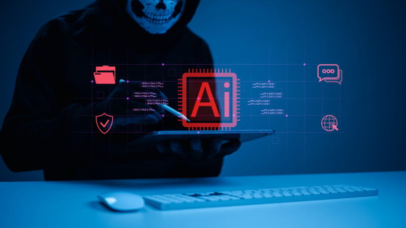 A masked hacker uses a tablet with a futuristic AI interface to launch a cyberattack. The concept illustrates cybersecurity threats, data breaches, risks associated with artificial intelligence, invasions of online privacy, and network systems.